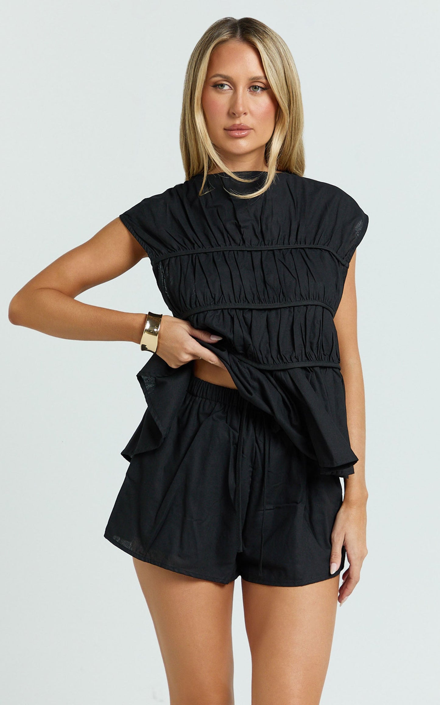 Conjunto de dos piezas: top con detalle fruncido y pantalones cortos en color negro.
